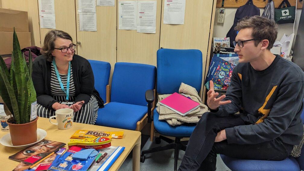 Two professionals sitting in an educational environment, talking.