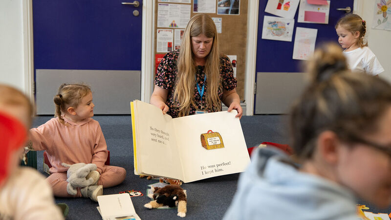 A woman sharing an open book with families