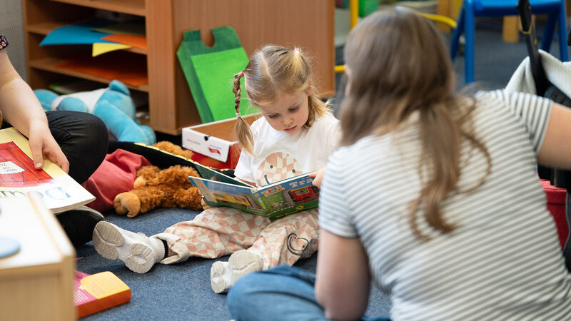 A girl sitting on the floor looking at a book