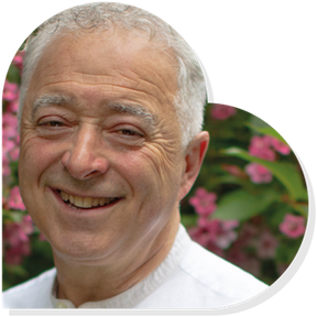 Frank Cottrell-Boyce smiling in a heart shape with foliage behind him