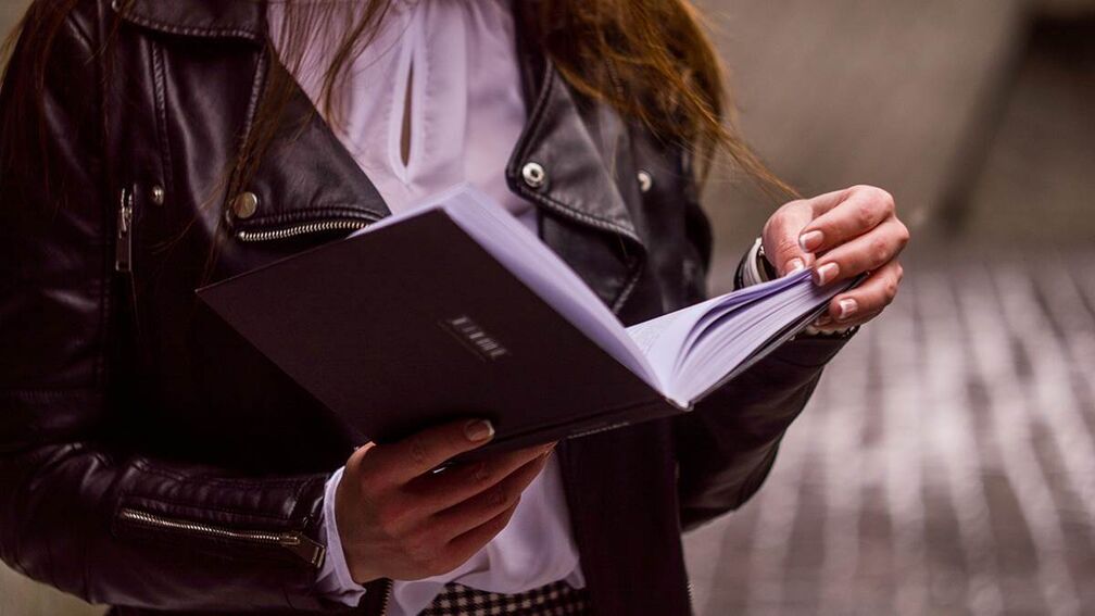 A girl holding a book, just about to turn the page.
