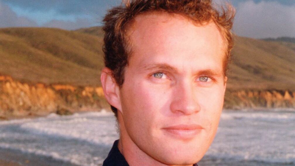 David Vann looking to camera, with the coast in the background.