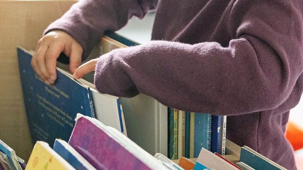 A close-up of a child choosing books from a box