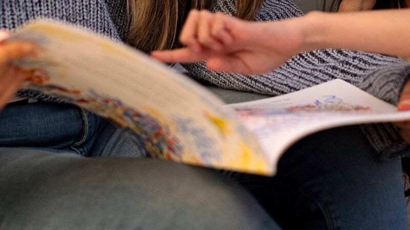 A close up of a woman and child reading a book together