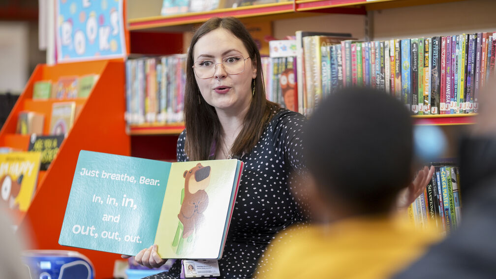 person reading out a story to children in a library