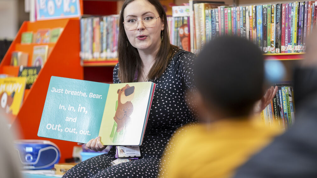 person reading out a story to children in a library