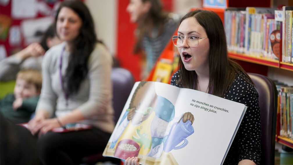 A woman sharing a story with bookshelves behind her
