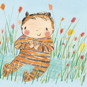 A child in a tiger stripe onesie smiling and sitting in a patch of flowers from the front cover of It's A Little Baby