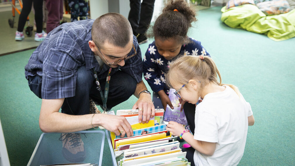 adult and two children choosing books from a box