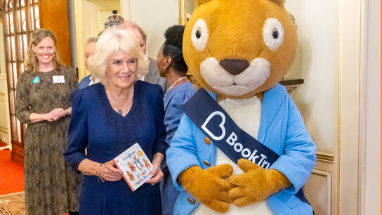 Her Majesty The Queen holding a copy of Four Happy Bunnies next to Peter Rabbit in a BookTrust sash at Clarence House