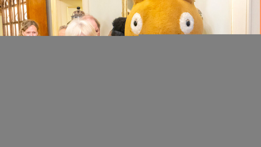 Her Majesty The Queen holding a copy of Four Happy Bunnies next to Peter Rabbit in a BookTrust sash at Clarence House