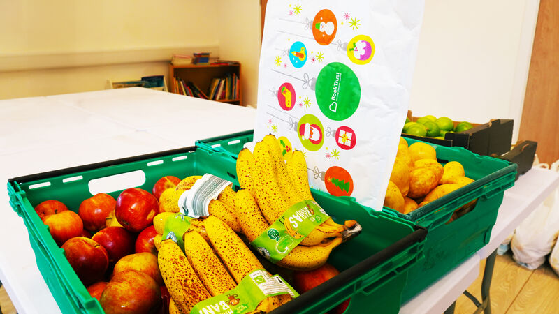 A table with crates of fruit and veg and a BookTrust Christmas bookpack