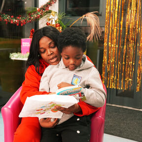 A mum and son sat reading together, with Christmas decorations in the background.