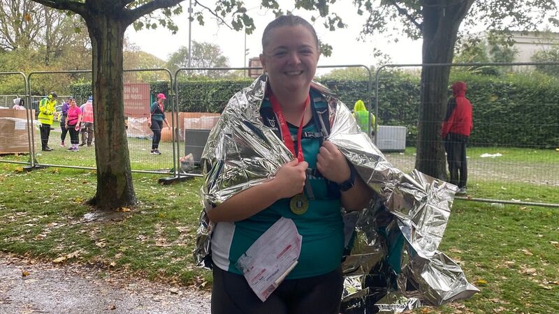 Jenna standing and smiling at camera after finishing her run wrapped in a silver space blanket