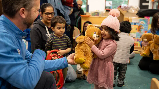 A photo of a child receiving a bear from Build-a-Bear and BookTrust
