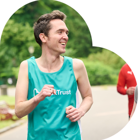 Man looking sideways whilst running wearing a teal running vest which has the BookTrust logo on it