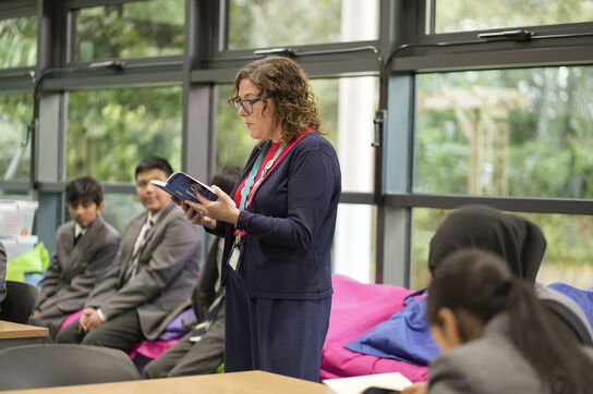 A female school librarian reading out one of the Bookspark books to a group of children