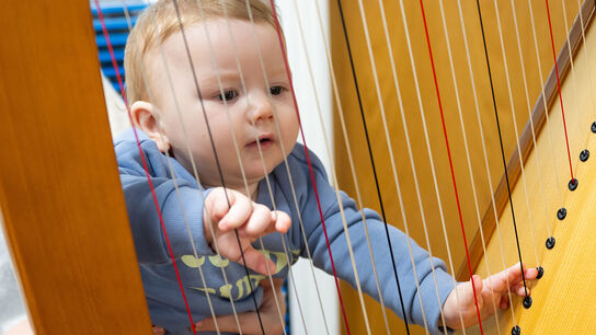 A baby playing with a harp while taking part in Big Welsh Rhyme Time