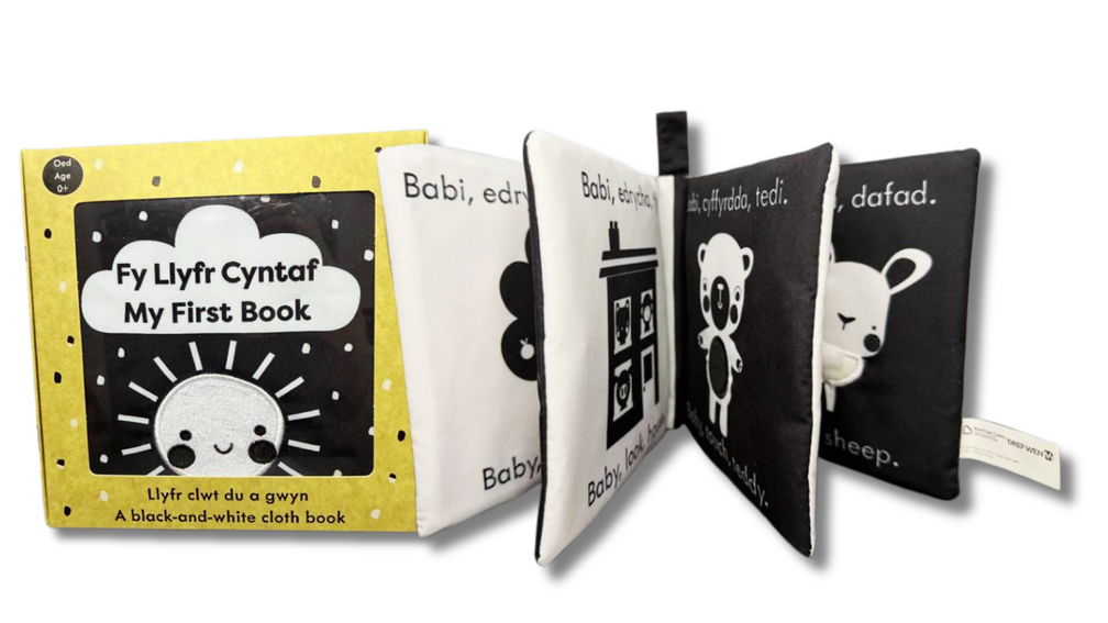 A close up of the cover and inside of the Baby Bundle Book showing black and white images alongside Welsh and English writing