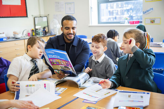 teacher and children looking at Bookbuzz Primary brochure