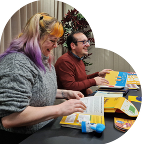 Heart image of Helen and Francesco sitting at a table with Bookstart books smiling and looking inside the books