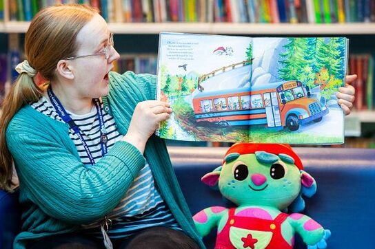 Woman showing a picture book to audience in a library