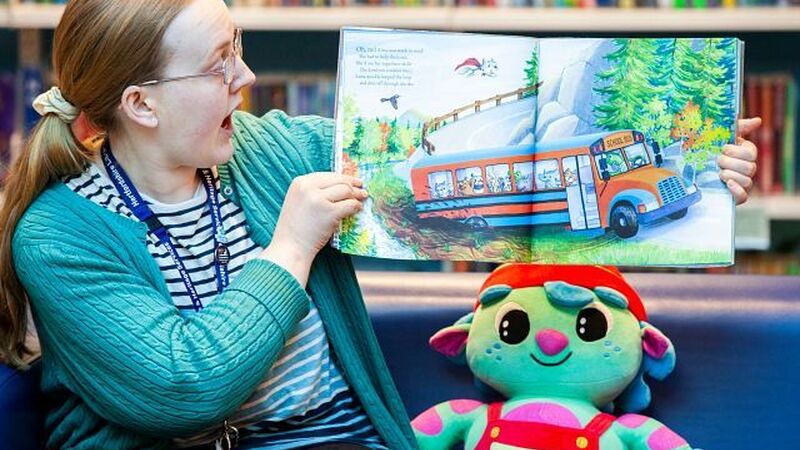 Woman showing a picture book to audience in a library