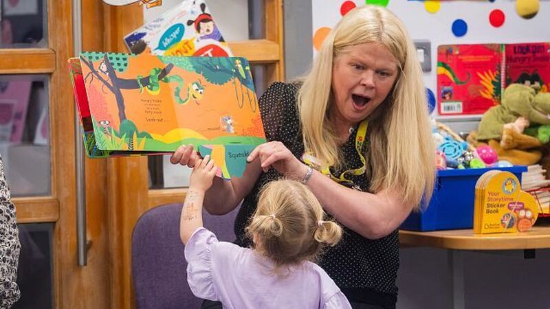 Child approaching picture book at storytime in a library