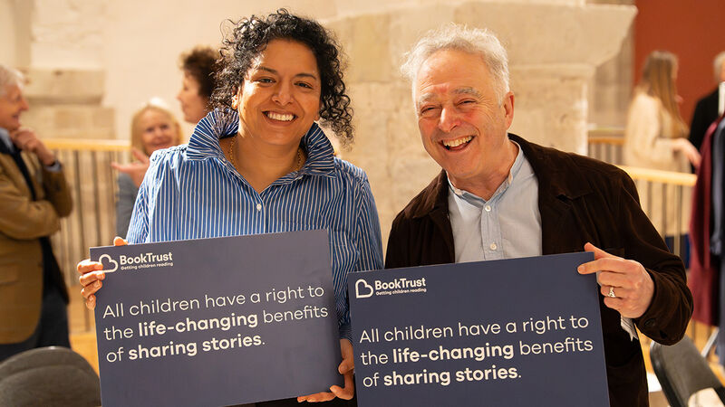 Author Nadia Shireen and Waterstones Children's Laureate Frank Cottrell-Boyce at the Reading Rights summit holding signs reading: "All children have a right to the life-changing benefits of sharing stories"