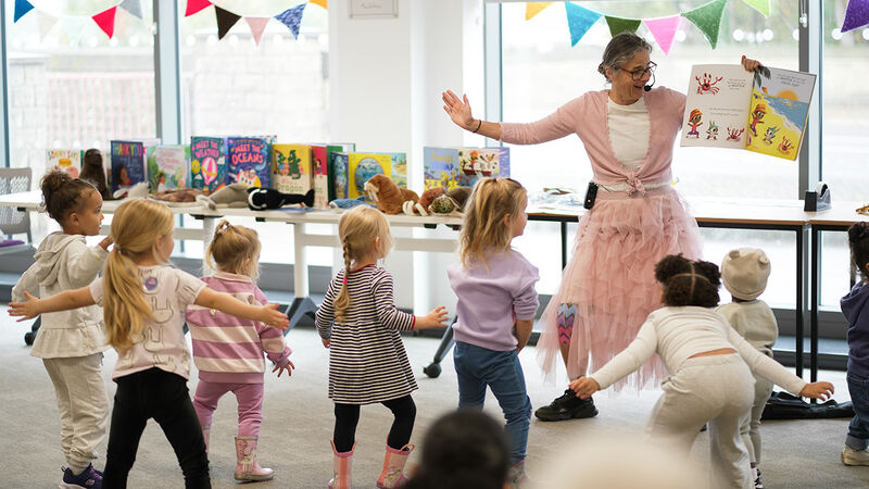 Caryl Hart leading a Jellyfish Jiggle story time session, with lots of young children dancing in front of her