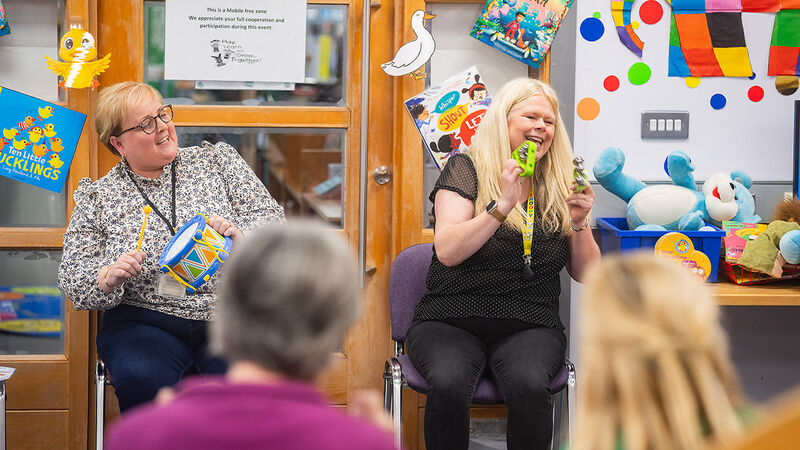 Two librarians with children's percussion instruments leading a rhyme time for families