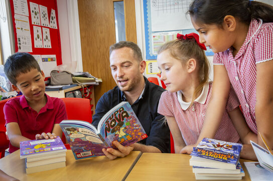 A teacher reading a book with primary school students