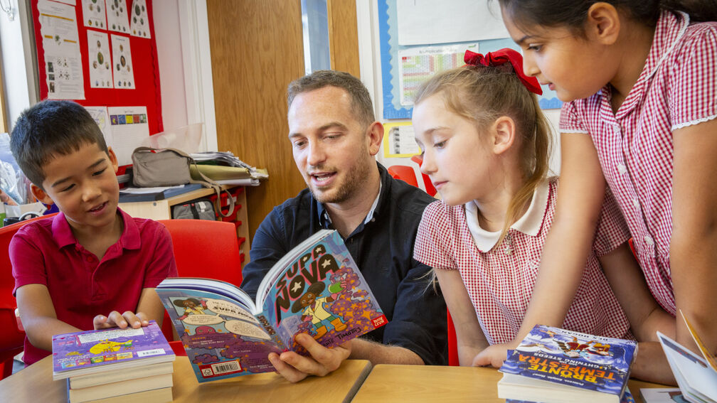 A teacher reading a book with primary school students