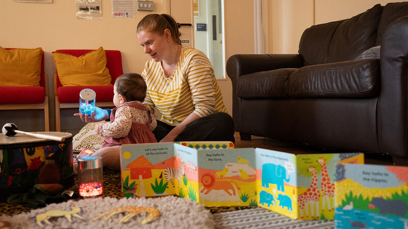 A mum and a baby in the family hub in Knowsley, with a fold-out book on the floor next to them