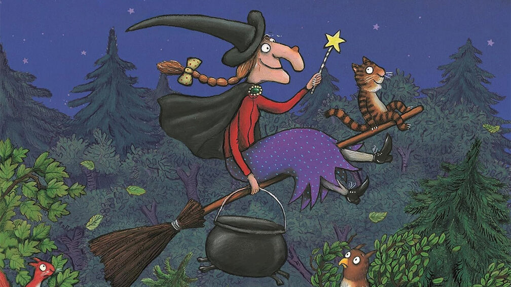 An illustration from the front cover of Room on the Broom - a witch sitting on a broomstick holding a cauldron and a wand, with a cat balanced on the front of the broomstick; they are flying above trees and surprised animals