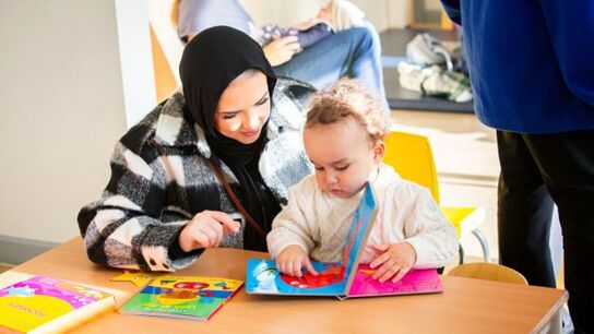 An early years professional supporting a young child in the classroom.