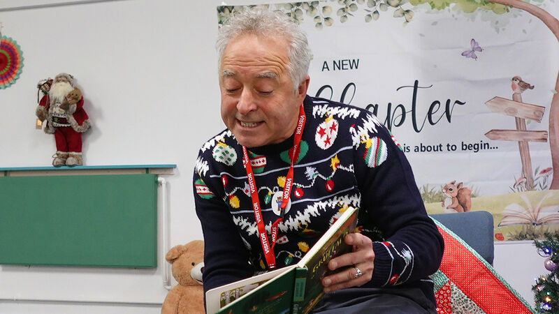 Frank Cottrell-Boyce wearing a Christmas jumper and reading The Gruffalo out loud