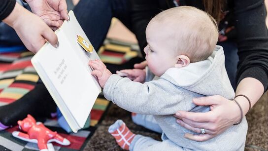 A baby at a Children's centre looking at a book