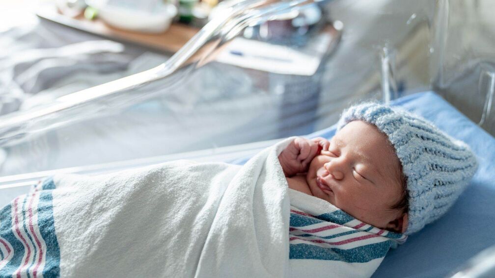 A photo of a baby sleeping in a hospital crib