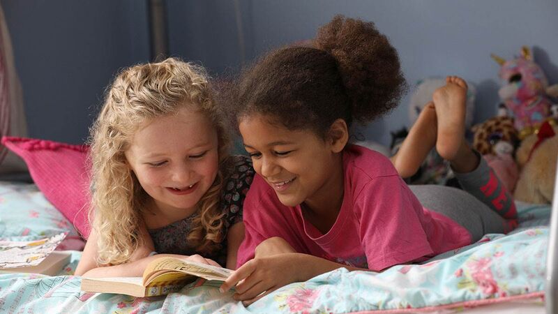 Two girls reading a book together indoors