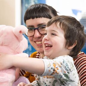 Child plays with puppet while laughing.