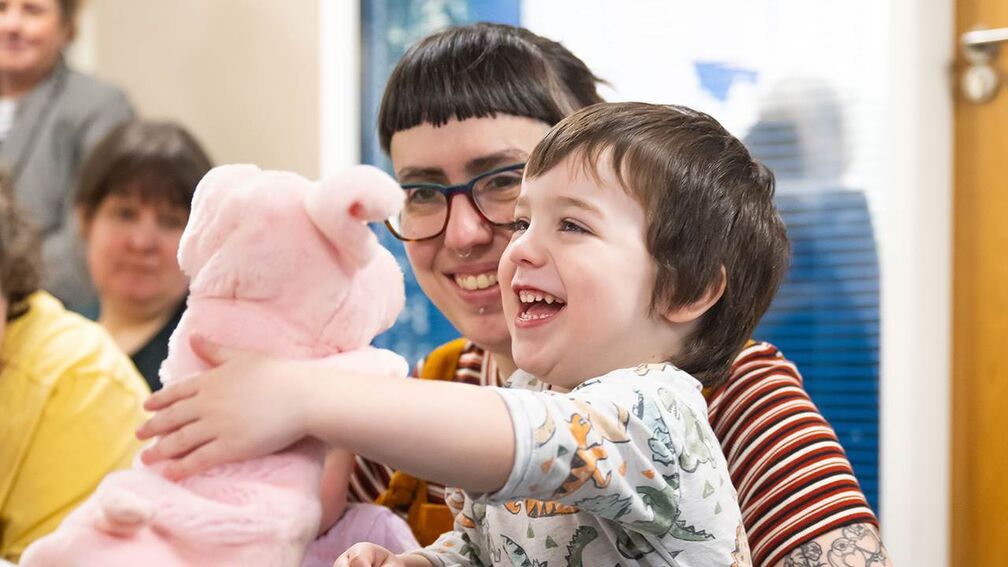 Child plays with puppet while laughing.