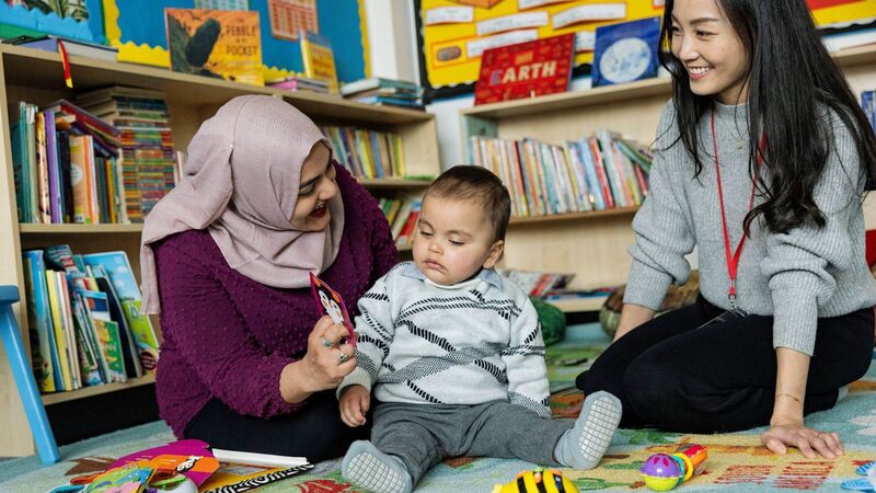 A young child in the classroom with two professionals.