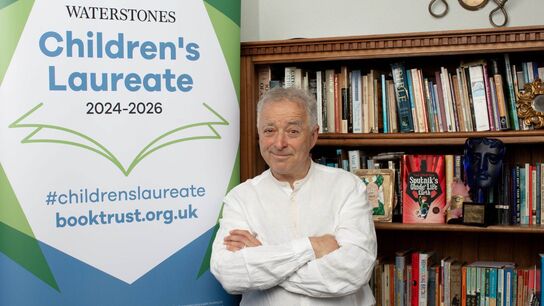 frank cottrell boyce standing next to banner stand and books