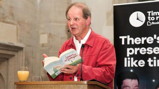 Michael presenting to an audience while holing a book.