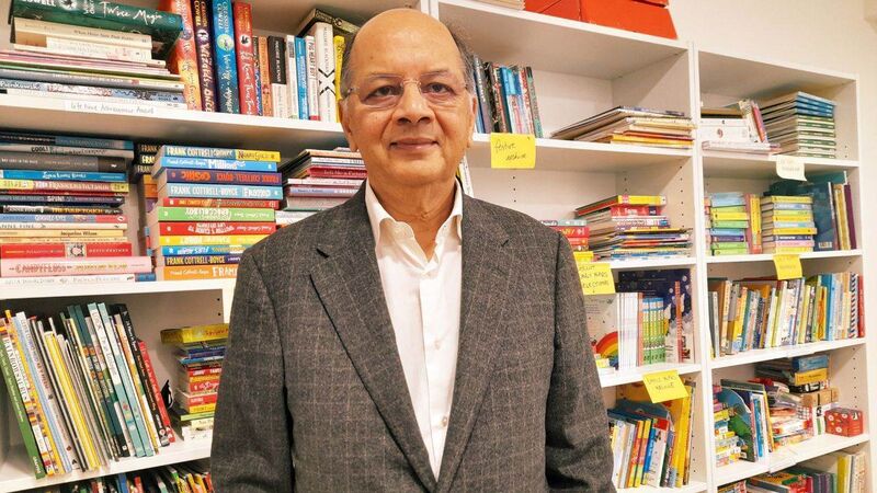 Gautam standing in front of a bookshelf, smiling.