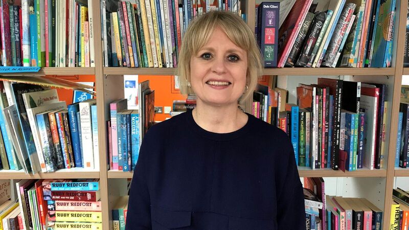 Hilary looking to camera and smiling, with books in the background.