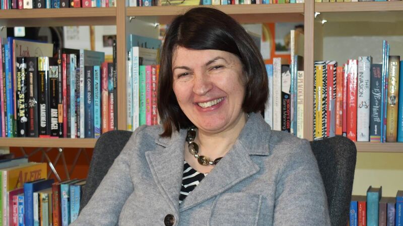 June looking to camera and smiling with books in the background.