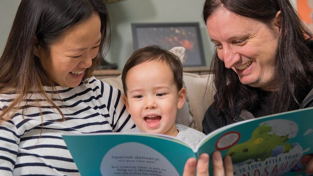 Carers and child reading together