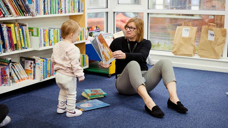 A librarian reading a story to a child in the library.
